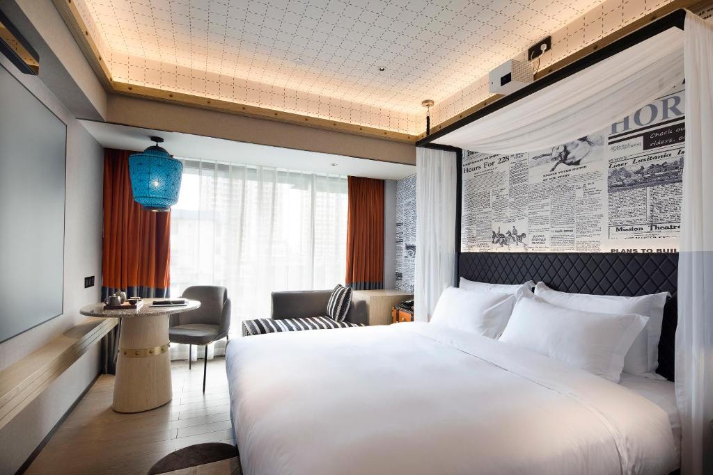 um quarto de hotel com uma cama grande e uma mesa em 广州塔骑士物语酒店-Arthur Hotel Canton Tower Guangzhou em Guangzhou