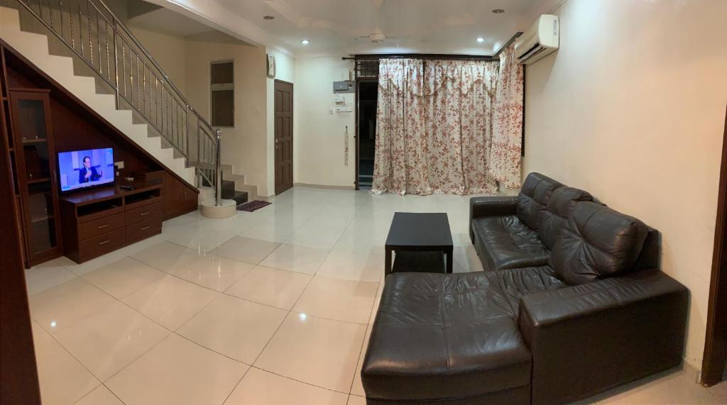 - un salon avec un canapé en cuir et une télévision dans l'établissement Awani Homestay, à Permatang Janggus