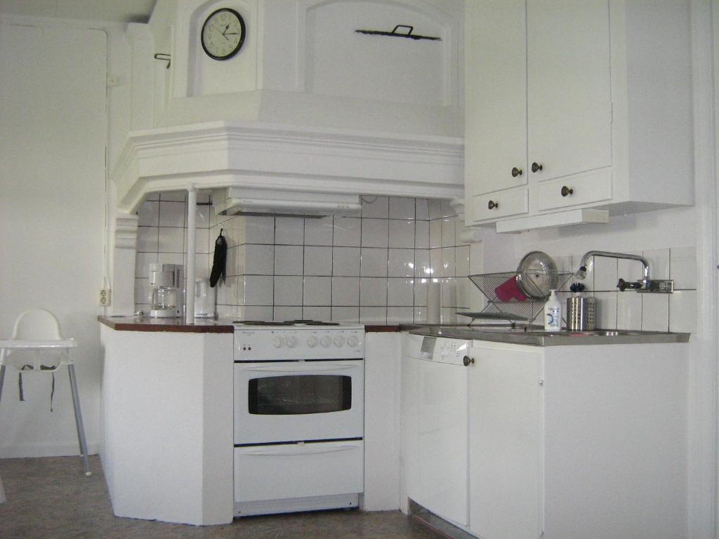 a white kitchen with a stove and a sink at Ulricehamn Nilsagården in Ulricehamn