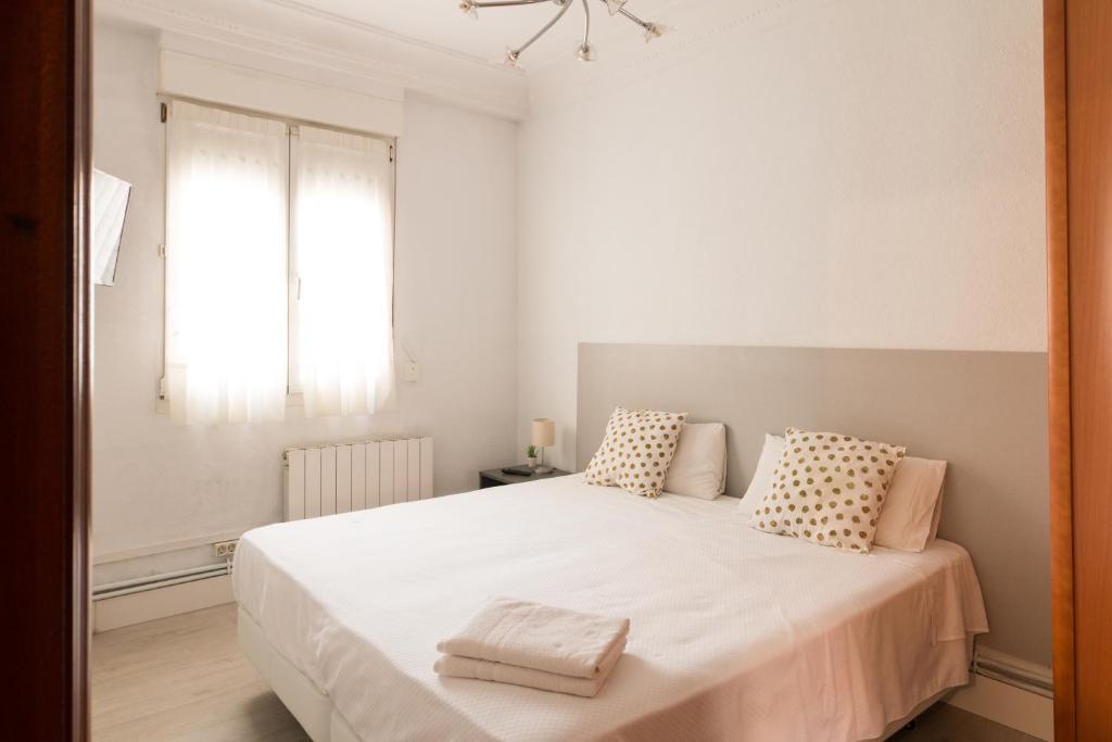 Un dormitorio con una gran cama blanca con dos almohadas. en Pensión Arias, en Bilbao