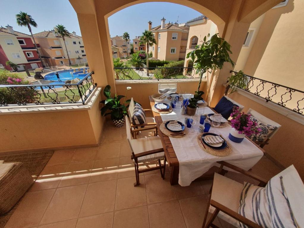una mesa y sillas en un balcón con piscina en Increíble Duplex 2 plantas vistas piscina Altaona Golf -Mosa, en Murcia