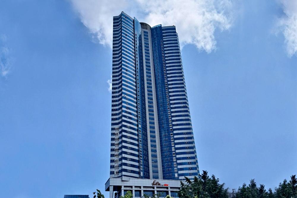 釜山的住宿－Felix by STX Hotel & Suite，一座高大的蓝色建筑,前面有树木