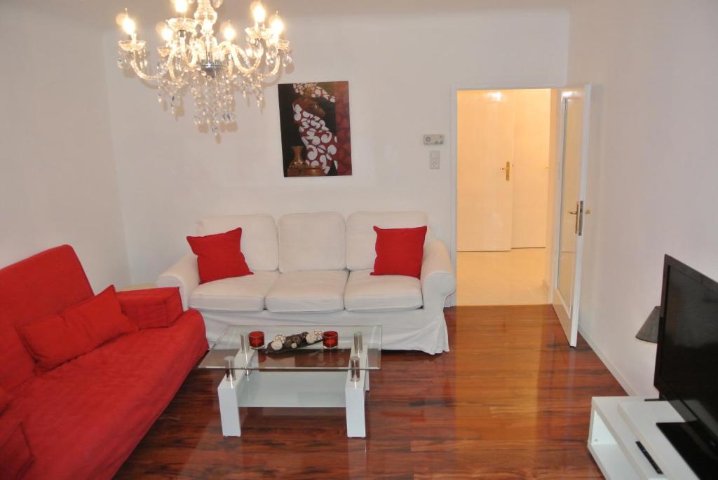 sala de estar con sofá blanco y almohadas rojas en Apartment Paradies - U1 Station altes Landgut, en Viena