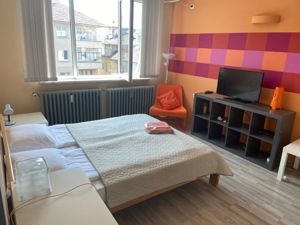 a small bedroom with a bed and a tv at Marina Apartment in Sofia