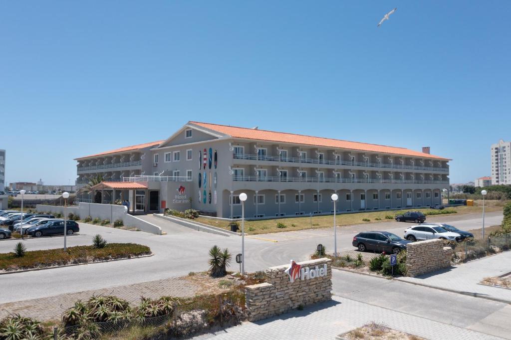 a large building with cars parked in a parking lot at Star inn Peniche in Peniche