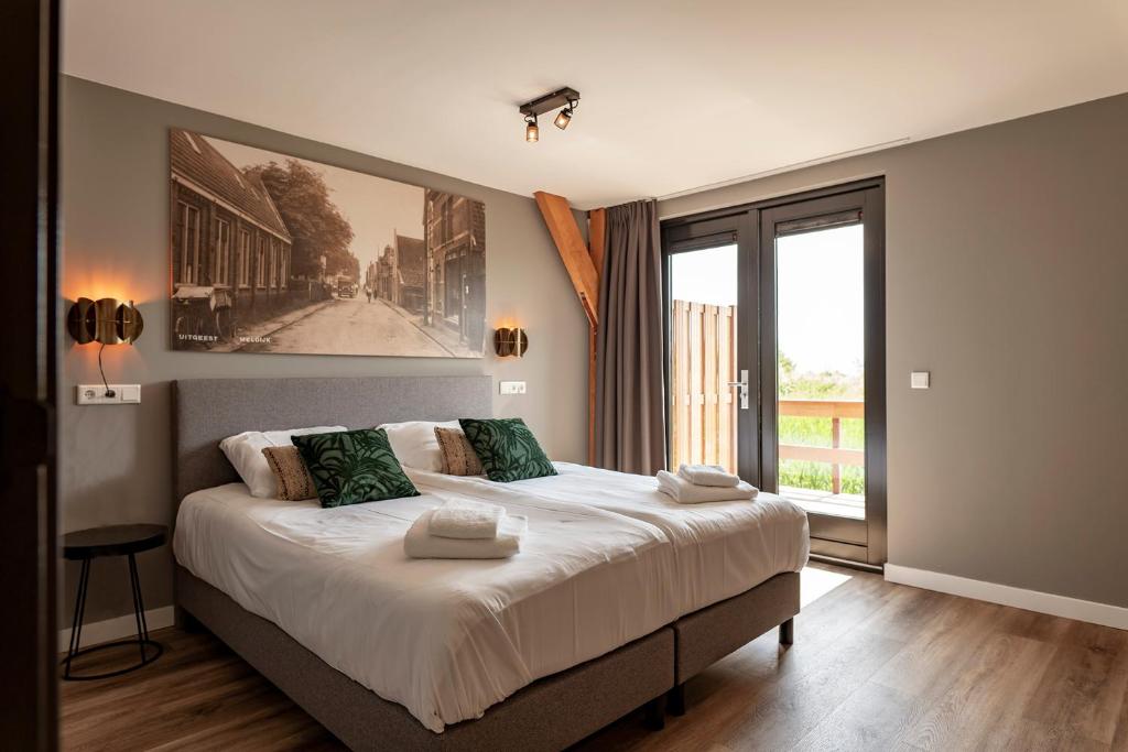 a bedroom with a large bed and a large window at Dutchen Erfgoedpark De Hoop Appartementen in Uitgeest