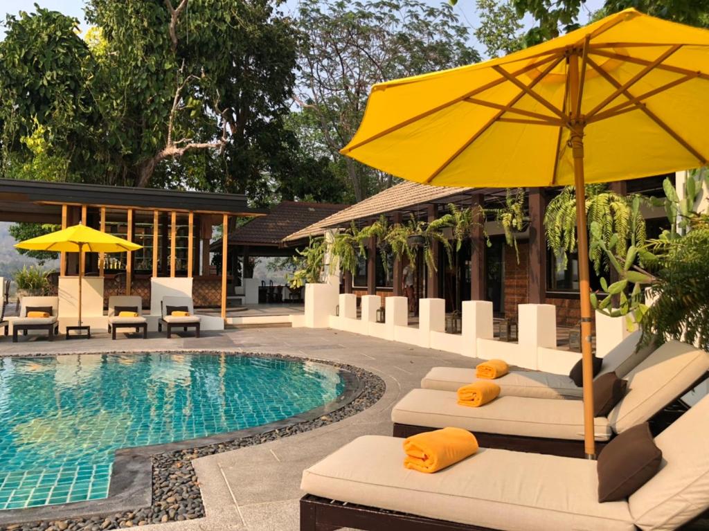 uma piscina com cadeiras e um guarda-sol ao lado de uma piscina em Tohsang Heritage Khongjiam em Khong Chiam