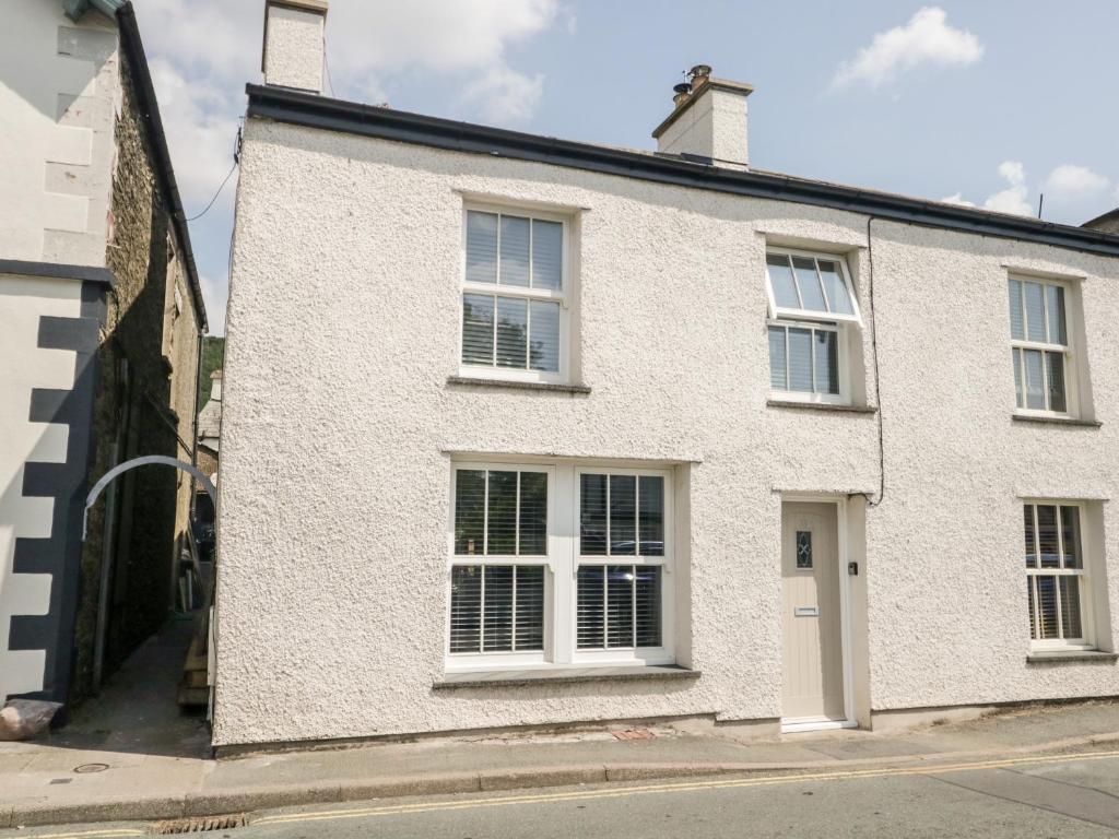a white house with white windows on a street at Hugill Cottage in Kendal