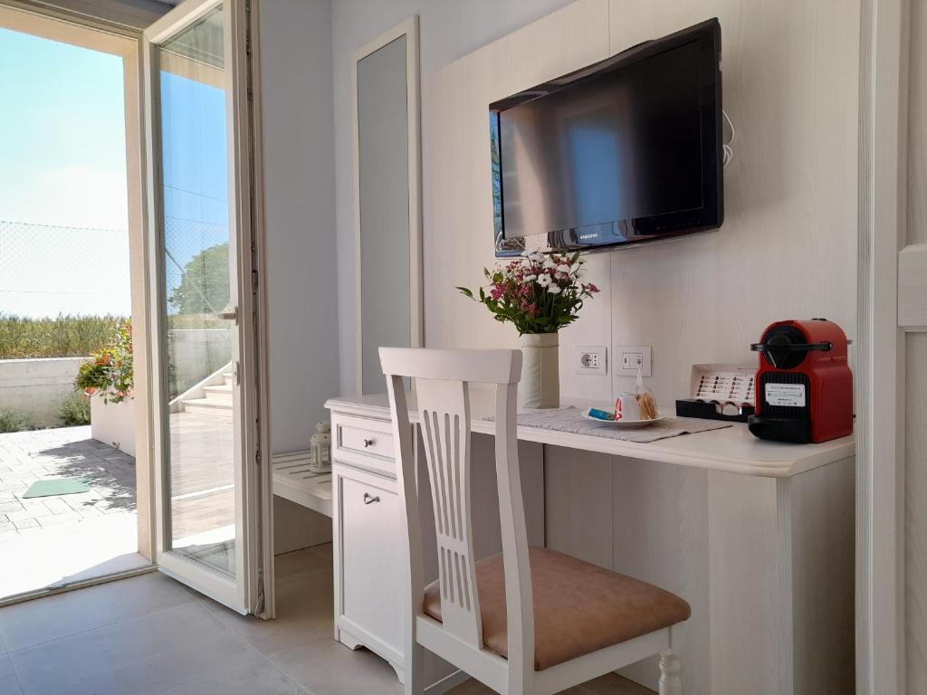 Habitación con escritorio, TV y silla. en B&B Camera e Caffè en Osimo
