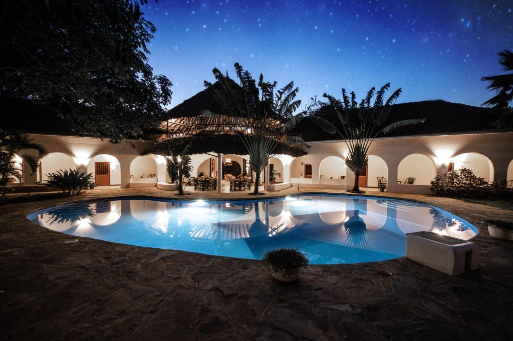 a house with a swimming pool at night at Zarafa House in Diani Beach