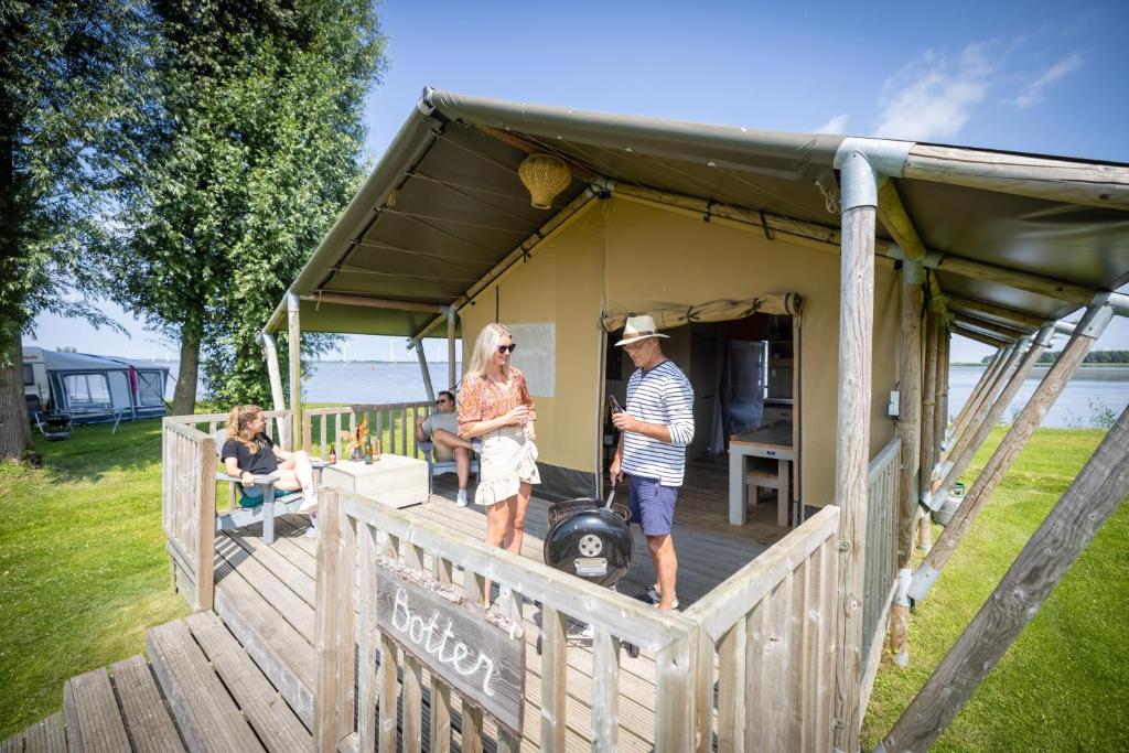 a man and woman standing on the porch of a tiny house at Jachthaven Nieuwboer in Bunschoten