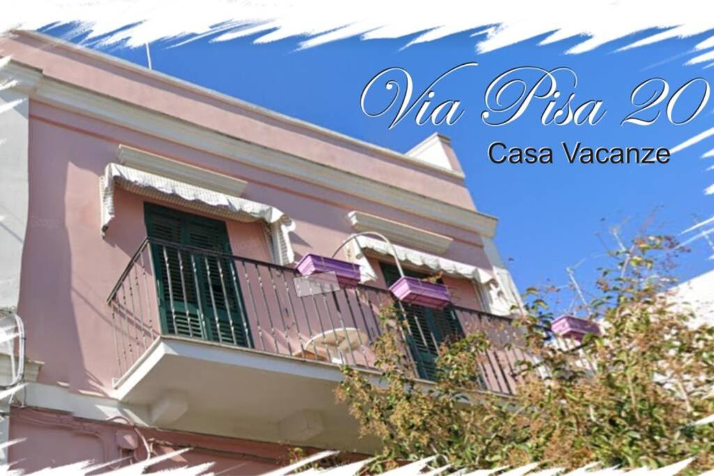 a pink building with a balcony with a dog on it at Via Pisa 20 Mansarda in Bari