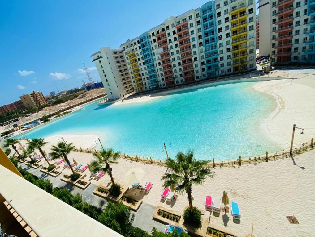 a large swimming pool with chairs and a beach at كريستال لاجونز بورتو جولف الساحل الشمالي in El Alamein