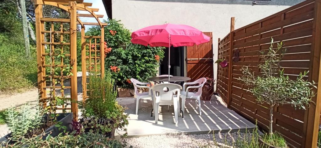 uma mesa e cadeiras com um guarda-sol rosa num pátio em Le Gîte du Chat Nature et Calme à la campagne em Villeneuve-de-Marc