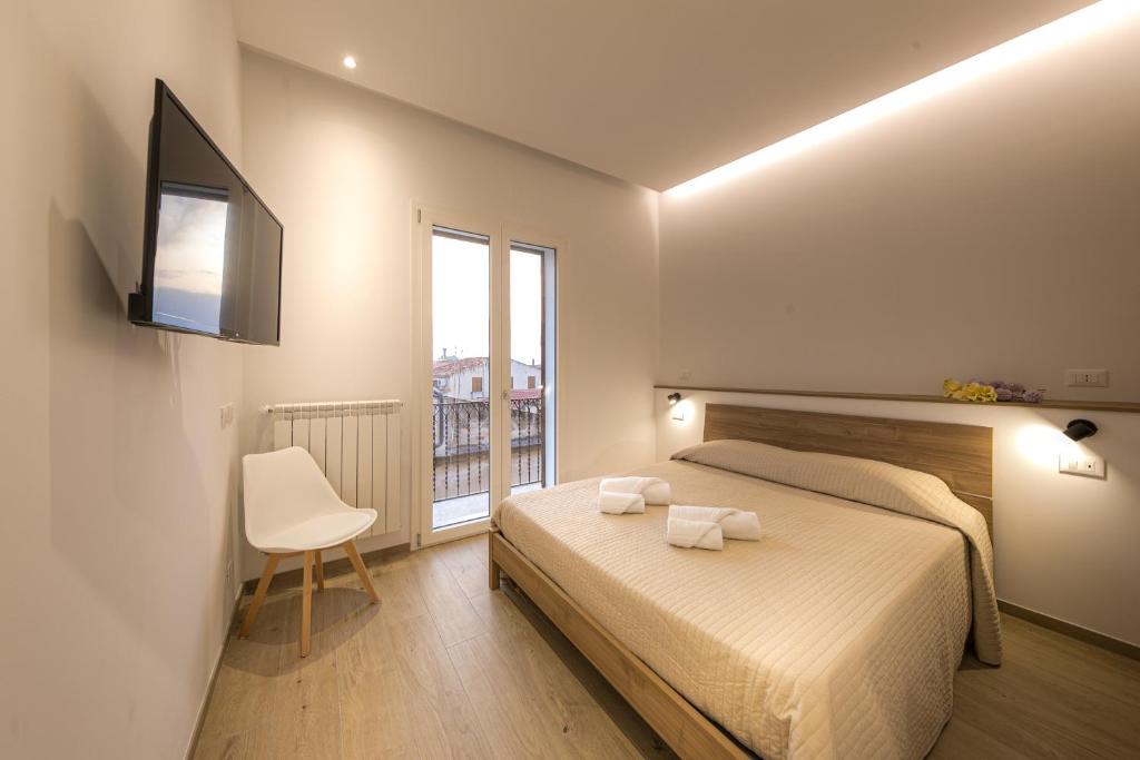 a bedroom with a bed and a chair and a window at CORESI rooms in Cefalù