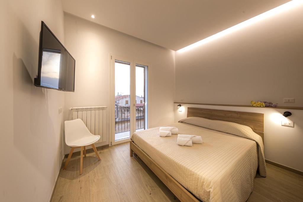 1 dormitorio con 1 cama, 1 silla y 1 ventana en CORESI rooms, en Cefalú