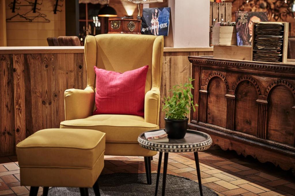 a yellow chair with a red pillow and a table at B&B Berglift direkt an der Talstation in Bad Hofgastein