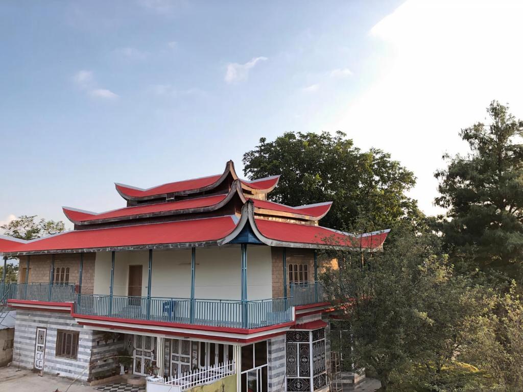 un edificio antiguo con techo rojo y árboles en Shangrilla House Murree, Bhurban, en Murree