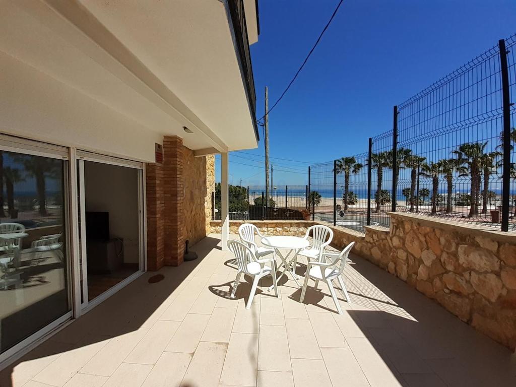 un patio con mesa, sillas y el océano en Apartamentos Dins Mar Apto. 3, en Torredembarra