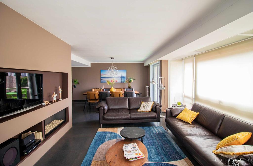a living room with a couch and a tv at Zeezicht Sibeac Koksijde in Koksijde