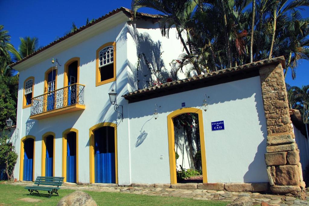 Casa blanca con puertas amarillas y banco en Pousada do Cais, en Paraty