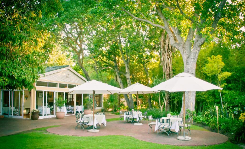 a patio with tables and chairs and umbrellas at Willowbrook Country House in Somerset West