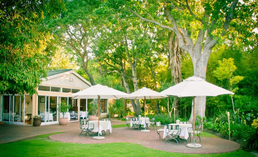 un patio avec des tables, des chaises et des parasols dans l'établissement Willowbrook Country House, à Somerset West