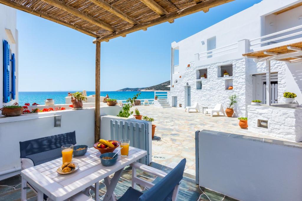 eine Terrasse mit einem Tisch, Stühlen und Meerblick in der Unterkunft Ammos Sifnos Village in Platis Gialos Sifnos