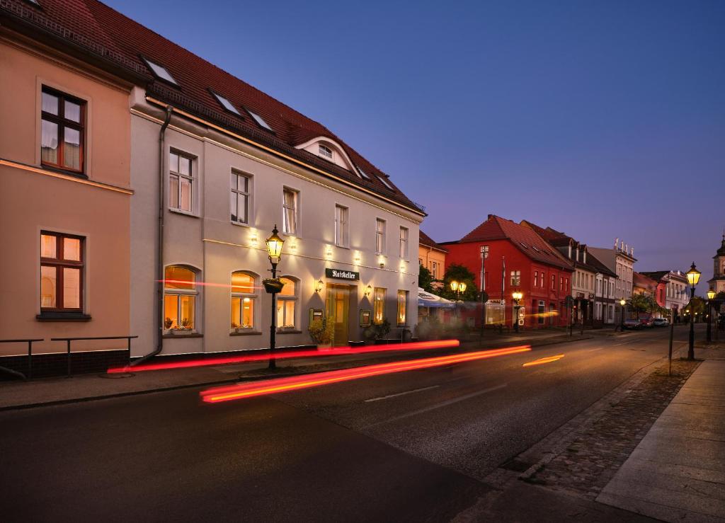 una calle de la ciudad por la noche con edificios y luces de la calle en Ratskeller Hotel & Restaurant Lindow, en Lindow