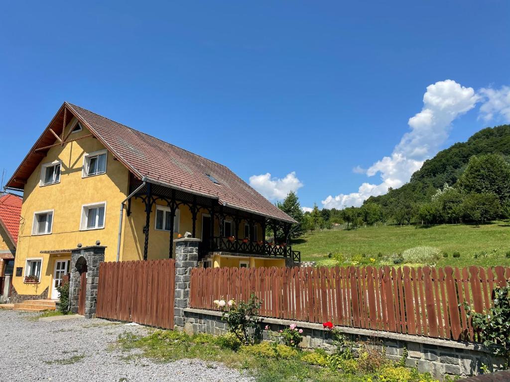 a yellow house with a fence in front of it at Kati Guesthouse in Corund