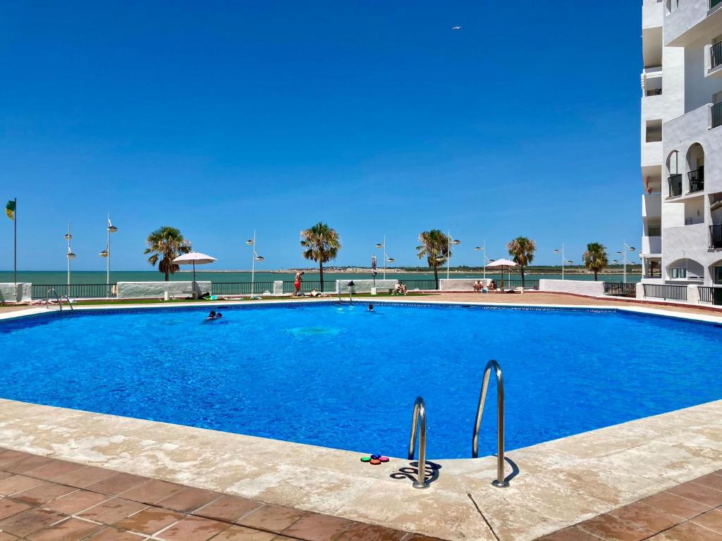 a large blue swimming pool next to a building at ESTUDIO BLEGAMAR TERRAZA - Playa, WiFi y Aparcamiento in El Puerto de Santa María