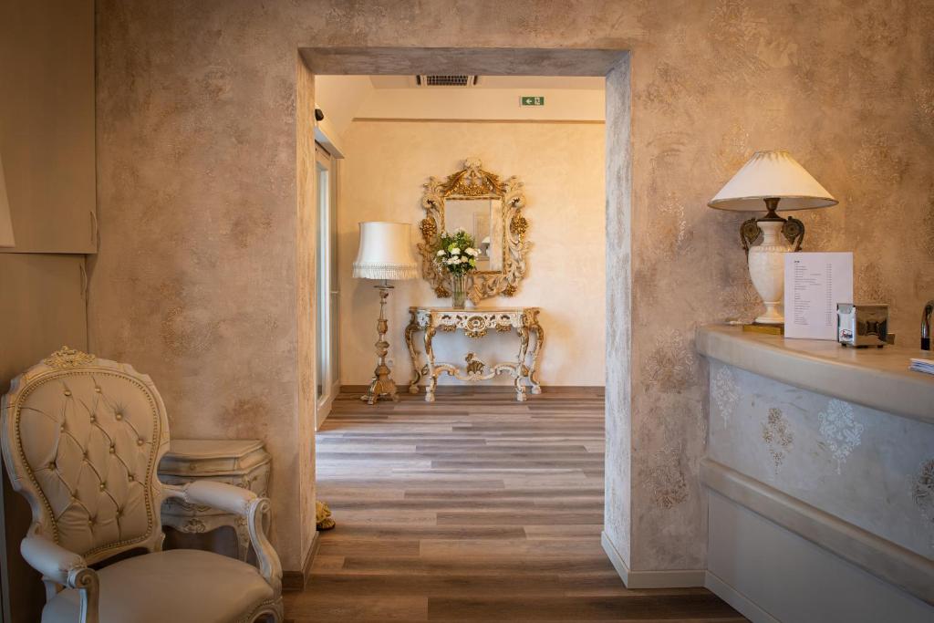 a hallway with a chair and a table and a mirror at Hotel Della Rosa in Ancona