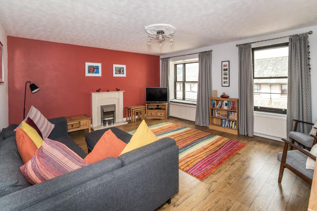 a living room with a gray couch and a red wall at Alban Rise in Keswick