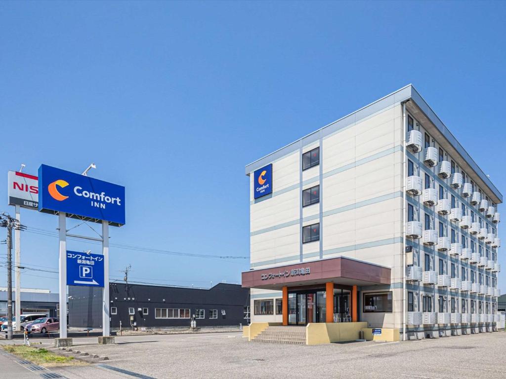 un gran edificio blanco con un cartel delante en Comfort Inn Niigata Kameda, en Niigata