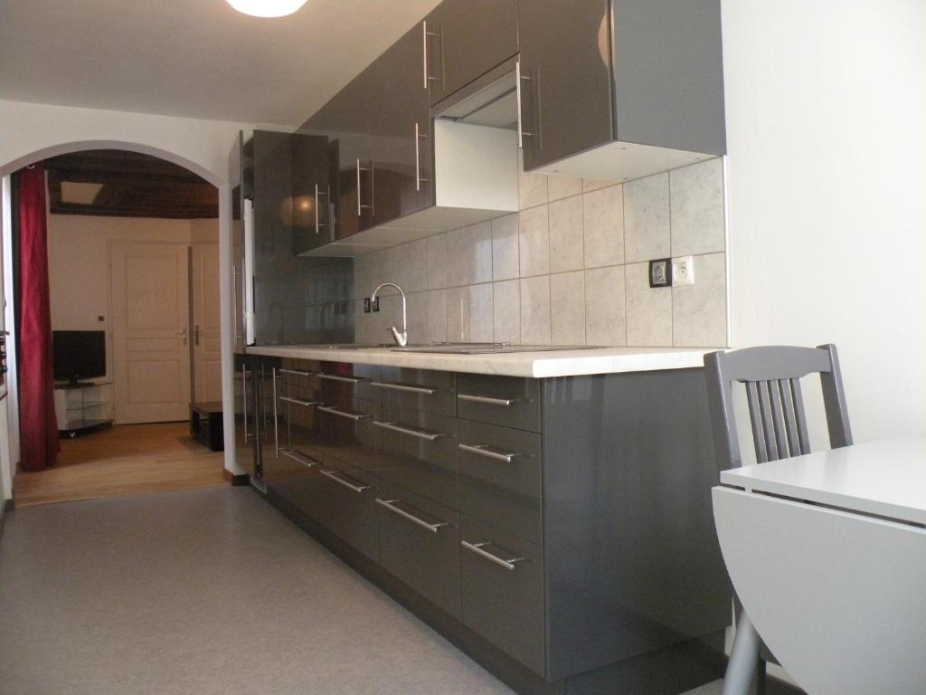 - une cuisine avec des placards noirs et un évier dans l'établissement Le salinois, à Salins-les-Bains