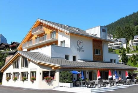 ein Gebäude mit Tischen und Stühlen davor in der Unterkunft Hotel Espen in Engelberg