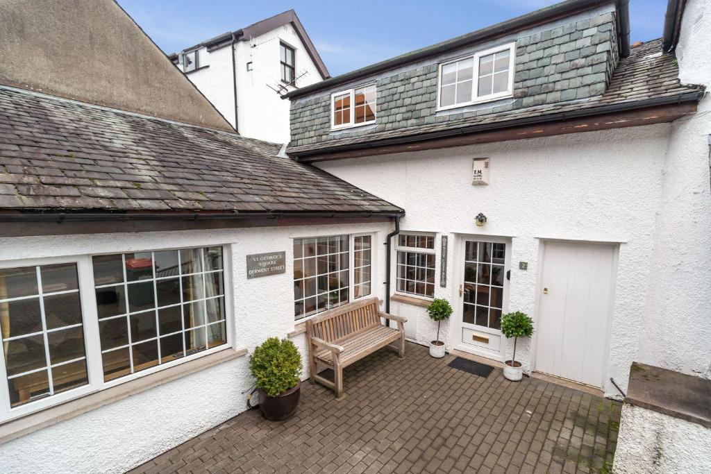 a white house with a bench on a patio at Daisy Cottage in Keswick
