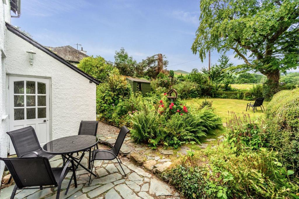 a patio with a table and chairs in a garden at Rose Bank Cottage in Braithwaite