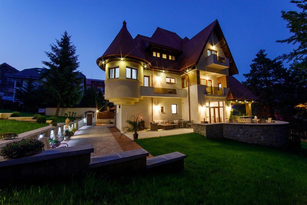 a large house with lights on the lawn at Moviliţa Residence in Sinaia