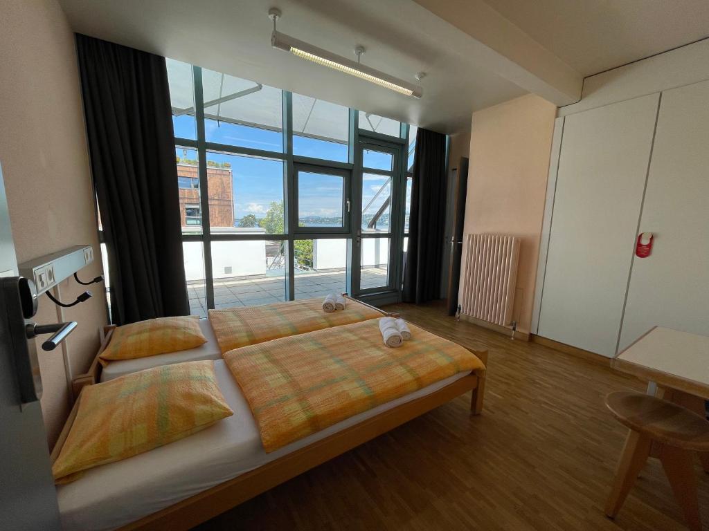 a bedroom with a large bed and a large window at Geneva Hostel in Geneva