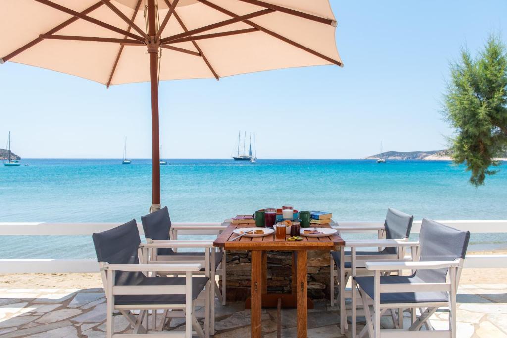 a table with chairs and an umbrella on the beach at Grandma's sifnos house in Platis Gialos