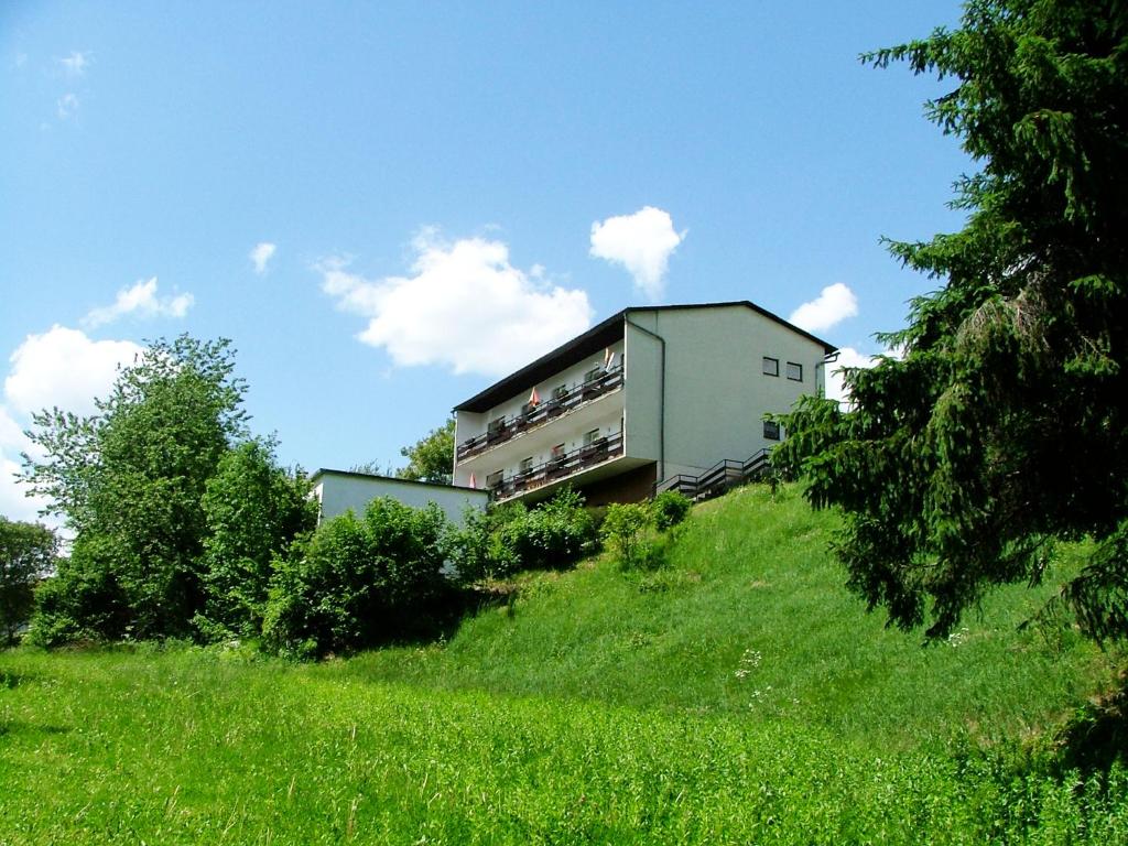 uma casa no topo de uma colina relvada em Pension Weiss em Drobollach am Faakersee