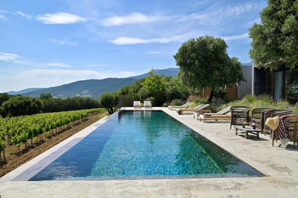 uma piscina no meio de um quintal com cadeiras e árvores em Domaine de Peretti della Rocca em Figari
