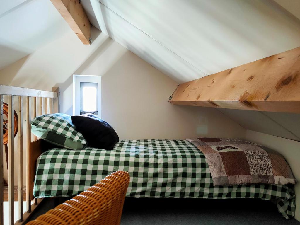 b&b de Wensput في De Moer: غرفة نوم بسرير اخضر وبيض في العلية