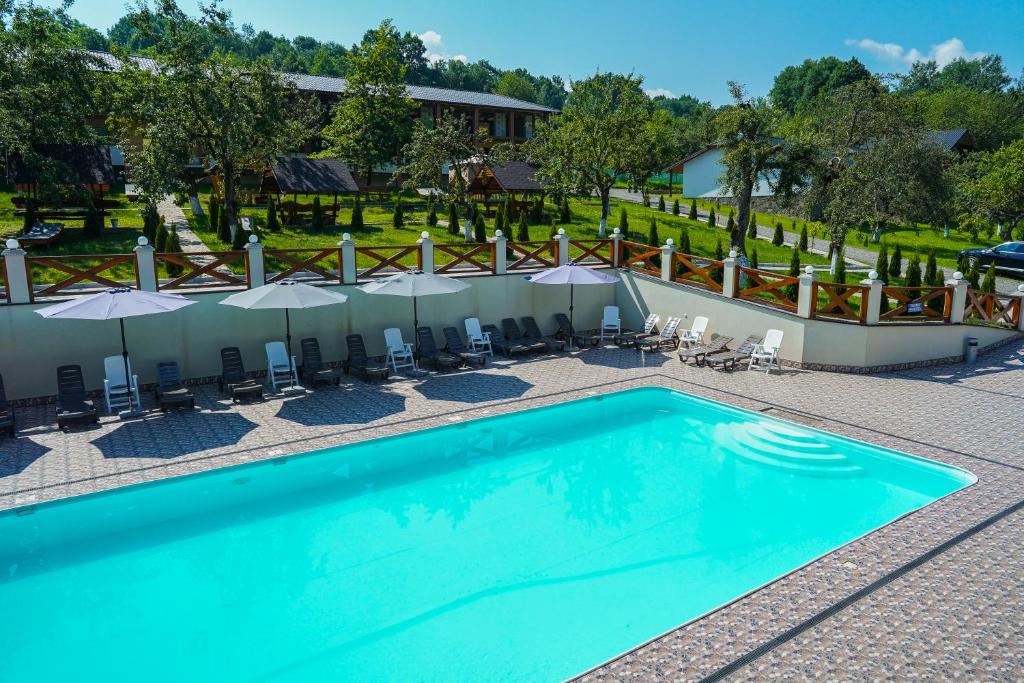 einen Pool in einem Hotel mit Stühlen und Sonnenschirmen in der Unterkunft Шаян Гора in Shayan