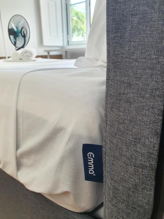 a bed with a white bedspread with a blue tag on it at Baixa Terrace Hostel in Faro