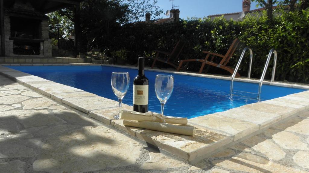 una botella de vino y 2 copas de vino junto a la piscina en Apartment Klesinger, en Poreč