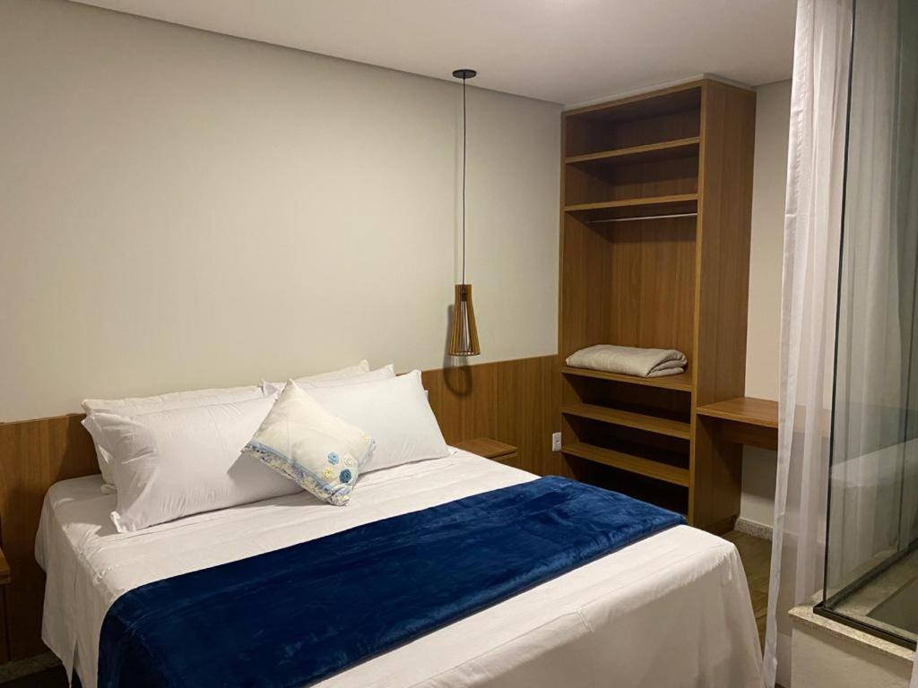 a bedroom with a white bed with a blue blanket at Canto das Pedras Flats in Alto Caparao