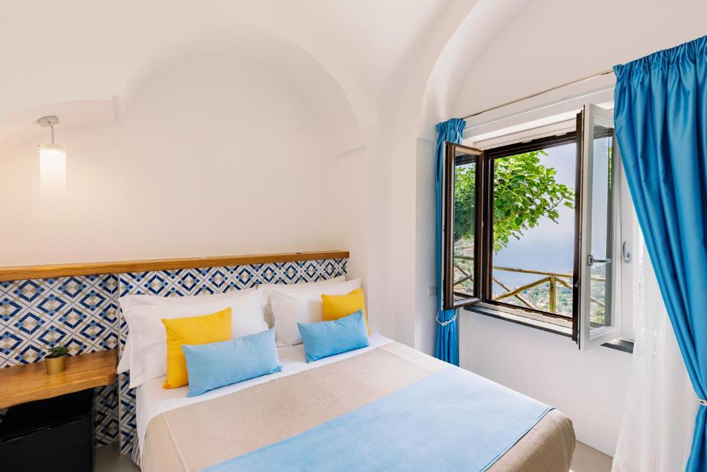 a bedroom with a bed with blue and yellow pillows at Monte Brusara Relais in Ravello