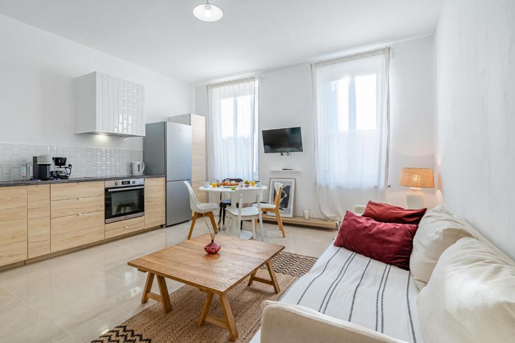 ein Wohnzimmer mit einem Sofa und einem Tisch in der Unterkunft Le Borély: Appartement climatisé avec 2 chambres, à 800m de la plage in Marseille